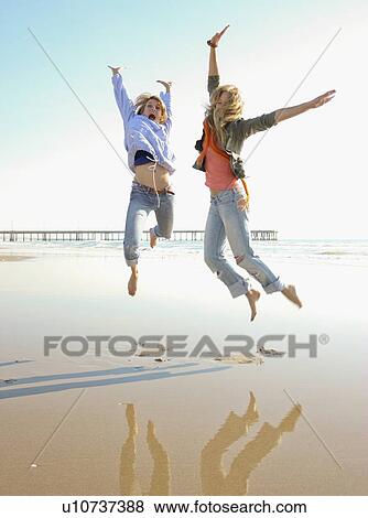 Stock Photo - Two women jumping on beach. Fotosearch