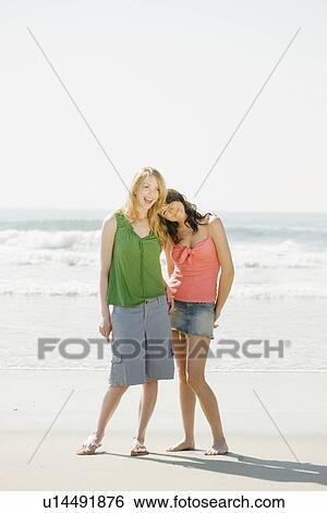 Two women standing on beach View Large Photo Image Stock Photograph - Two women standing on beach. Fotosearch
