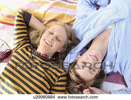 Two young women laying on blanket View Large Photo Image Picture - Two young women laying on blanket. Fotosearch