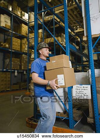 Picture - Warehouse worker carrying stack of boxes. Fotosearch