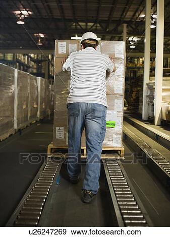 Stock Photo - Warehouse worker pushing palette. Fotosearch