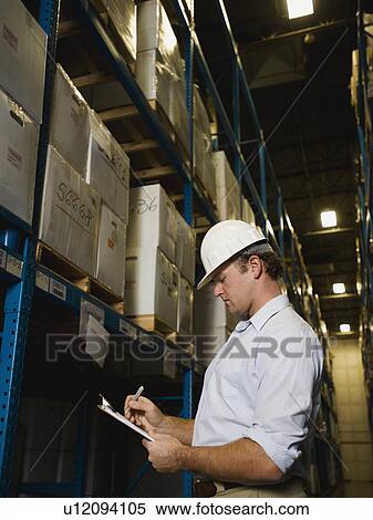 Stock Photography - Warehouse worker writing on clipboard. Fotosearch