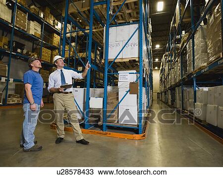 Stock Image - Warehouse workers checking inventory. Fotosearch