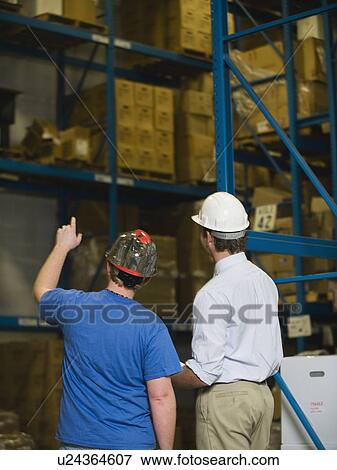 Warehouse workers looking at inventory View Large Photo Image Stock Photo - Warehouse workers looking at inventory. Fotosearch