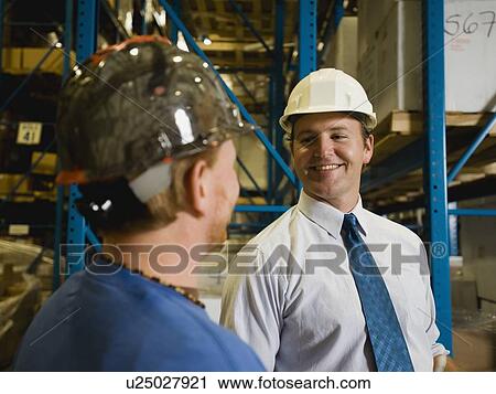 Warehouse workers smiling at each other View Large Photo Image Stock Image - Warehouse workers smiling at each other. Fotosearch