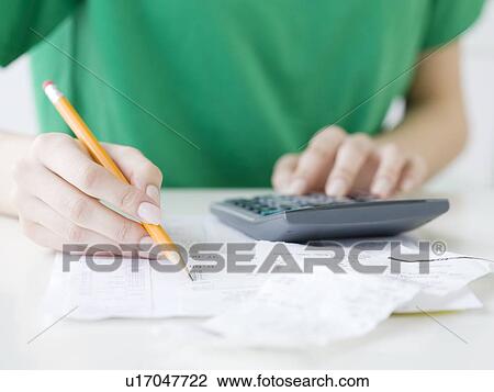 Stock Image - Woman adding receipts. Fotosearch