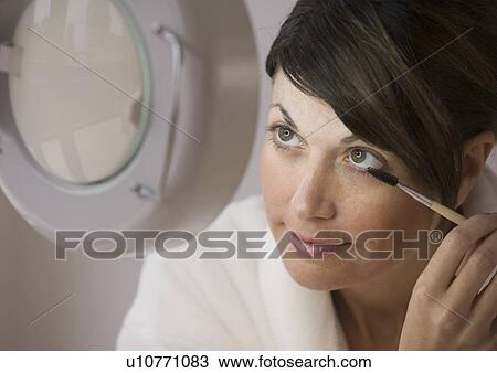 Stock Image - Woman applying makeup vanity mirror. Fotosearch