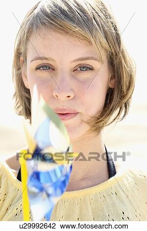 Stock Image - Woman blowing on pinwheel. Fotosearch