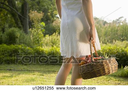 Stock Photography - Woman carrying basket of fresh tomatoes. Fotosearch