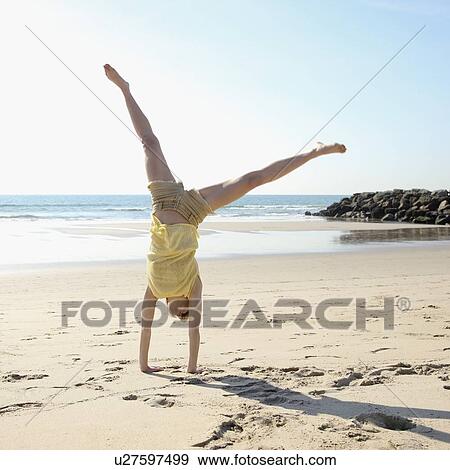 Stock Photo - Woman doing cartwheel on beach. Fotosearch