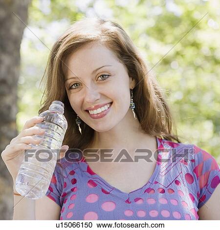 Woman drinking bottled water outdoors View Large Photo Image Stock Image - Woman drinking bottled water outdoors. Fotosearch