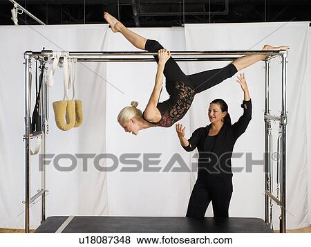 Stock Photo - Woman exercising on pilates equipment. Fotosearch