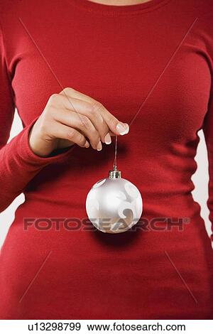 Stock Photo - Woman holding Christmas ornament. Fotosearch
