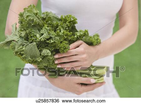 Stock Photograph - Woman holding fresh kale. Fotosearch