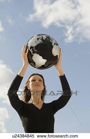 Stock Photography - Woman holding globe overhead. Fotosearch
