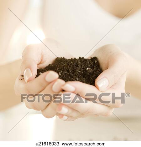 Stock Image - Woman holding handful of soil. Fotosearch