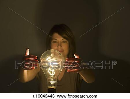Woman holding hands around large light bulb View Large Photo Image Stock Image - Woman holding hands around large light bulb. Fotosearch