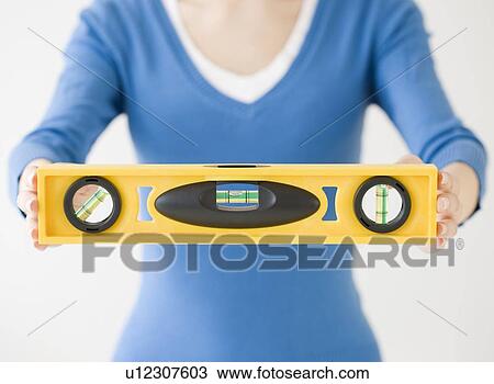 Stock Image - Woman holding level tool. Fotosearch