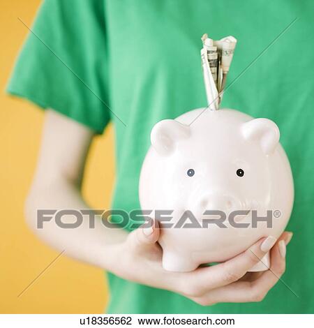 Woman holding piggy bank with money in slot View Large Photo Image Stock Image - Woman holding piggy bank with money in slot. Fotosearch