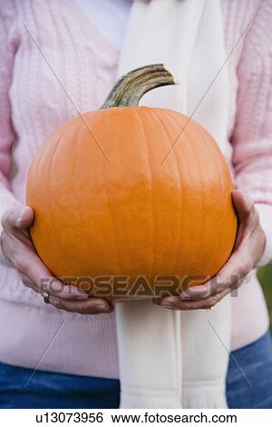 Stock Photograph - Woman holding pumpkin. Fotosearch
