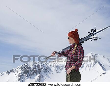 Stock Image - Woman holding skis on shoulder. Fotosearch
