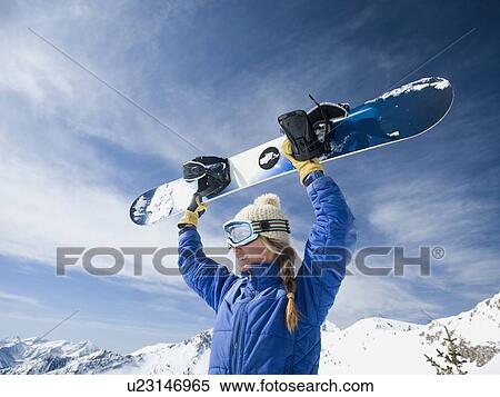 Stock Photography - Woman holding snowboard over head. Fotosearch