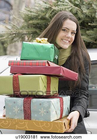 Stock Image - Woman holding stack of Christmas gifts. Fotosearch