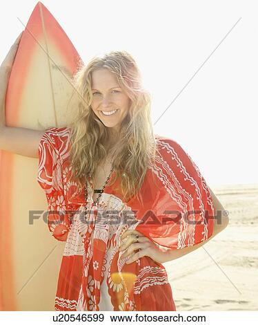 Woman holding surfboard on beach View Large Photo Image Stock Photo - Woman holding surfboard on beach. Fotosearch