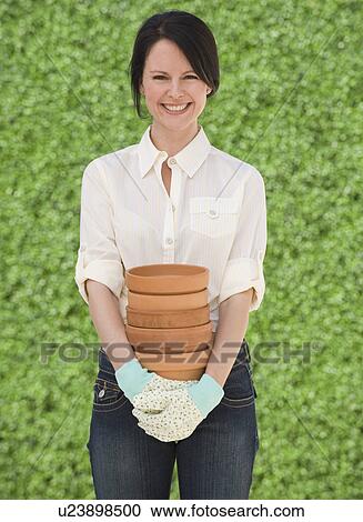 Stock Image - Woman holding terra cotta pots. Fotosearch