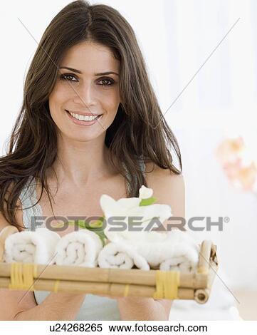 Stock Photography - Woman holding tray of rolled towels. Fotosearch
