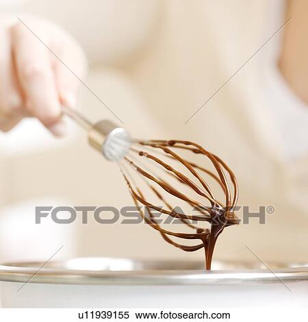 Stock Photography - Woman holding whisk with chocolate batter. Fotosearch