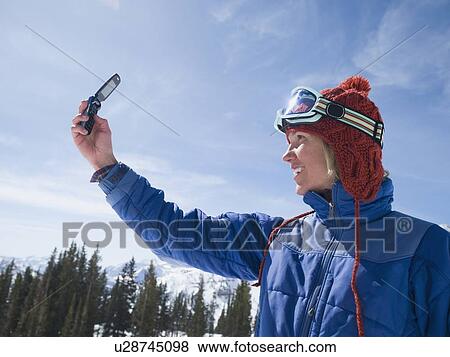 Stock Photo - Woman in ski gear taking photograph. Fotosearch