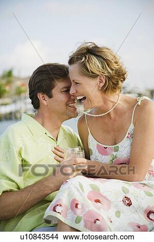 Picture - Woman laughing while husband bites necklace. Fotosearch