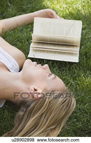 Woman laying in grass with book View Large Photo Image Stock Photo - Woman laying in grass with book. Fotosearch