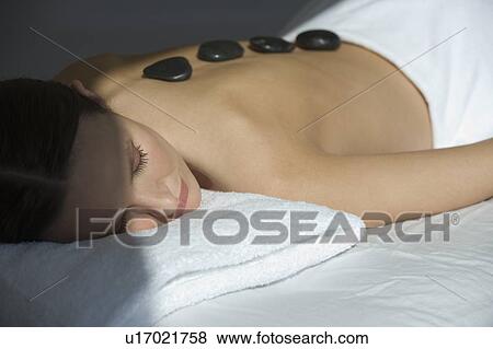 Stock Photo - Woman laying on massage table with warm stones on back. Fotosearch