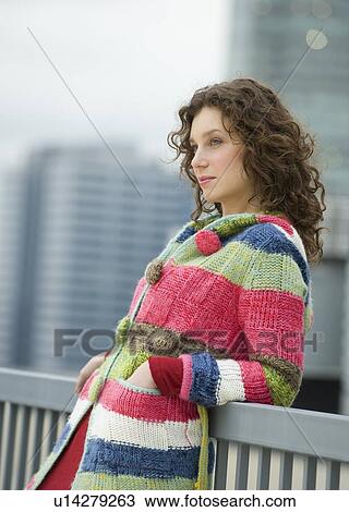 Stock Image - Woman leaning against railing. Fotosearch