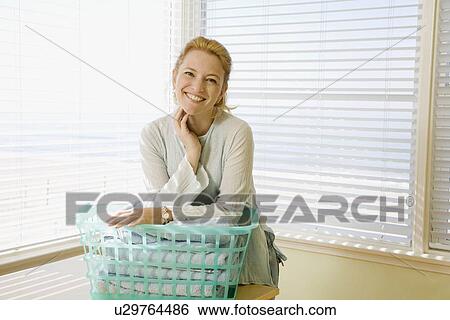 Stock Photograph - Woman leaning on laundry basket. Fotosearch