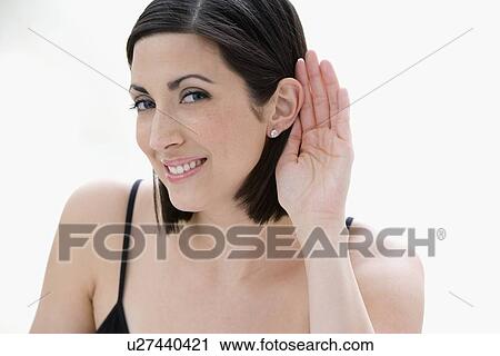 Stock Image - Woman listening with hand next to ear. Fotosearch