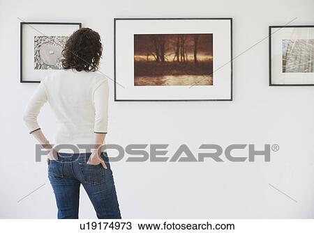 Stock Image - Woman looking at art in art gallery. Fotosearch