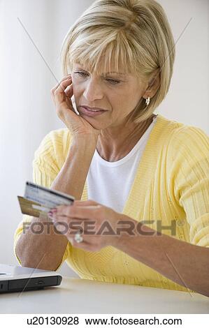 Woman looking at credit cards with concern View Large Photo Image Stock Photo - Woman looking at credit cards with concern. Fotosearch