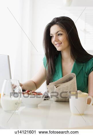 Stock Image - Woman looking at laptop in morning. Fotosearch