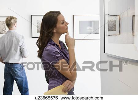 Stock Photograph - Woman looking at picture in art gallery. Fotosearch