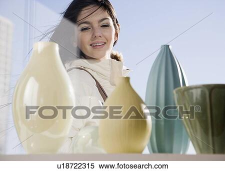 Stock Photography - Woman looking at pottery in window. Fotosearch