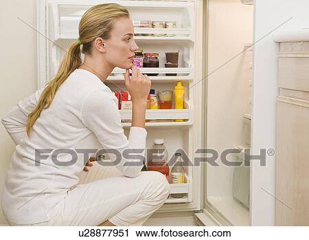 Stock Image - Woman looking inside refrigerator. Fotosearch