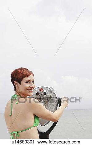 Woman looking through coin-operated binoculars View Large Photo Image Stock Image - Woman looking through coin-operated binoculars. Fotosearch