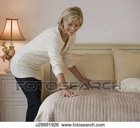 Woman making bed View Large Photo Image Stock Photograph - Woman making bed. Fotosearch