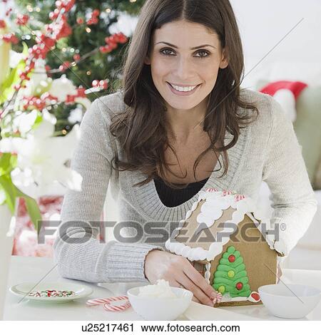Stock Image - Woman making gingerbread house. Fotosearch