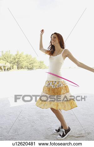 Stock Image - Woman on beach with hula hoop. Fotosearch
