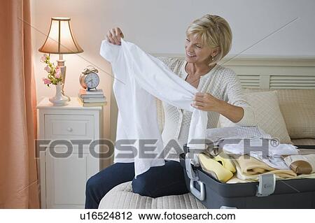 Stock Image - Woman packing suitcase. Fotosearch