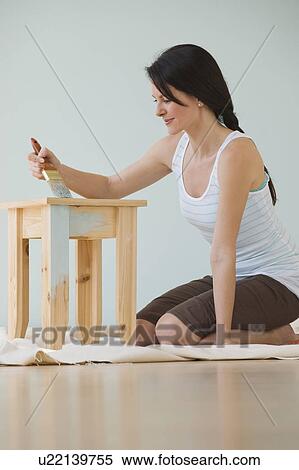 Stock Photography - Woman painting wooden table. Fotosearch